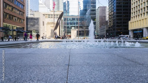 Chicago,Illinois/United States-April 16th, 2019: Time lapse of people having fun on a sunny spring afternoon near the Chicago downtown Daley center water fountain. the sun cast on the architecture  photo