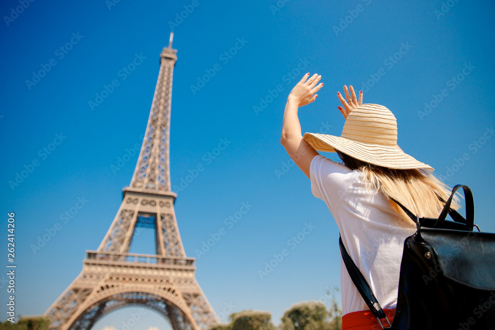 Young student girl with backpack rejoices Eiffel Tower, hands are directed up, Paris, France