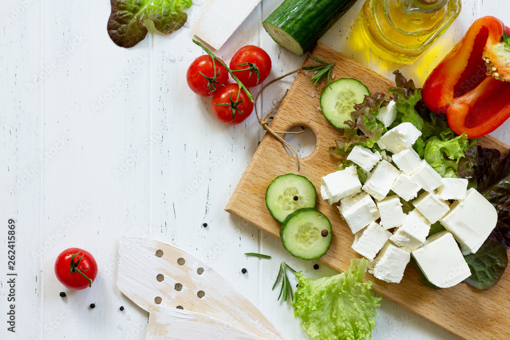 Ingredients for cooking qreek salad with fresh vegetables, feta cheese and black olives on wooden table. Top view flat lay background. Ingredients for cooking qreek salad with fresh vegetables, feta cheese and black olives on wooden table. Top view flat lay background.