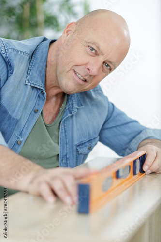 man measuring wood piece for furniture assembling