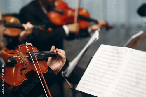 Elegant string quartet performing at wedding reception in restaurant, handsome man in suits playing violin and cello at theatre play orchestra close-up, music concept photo