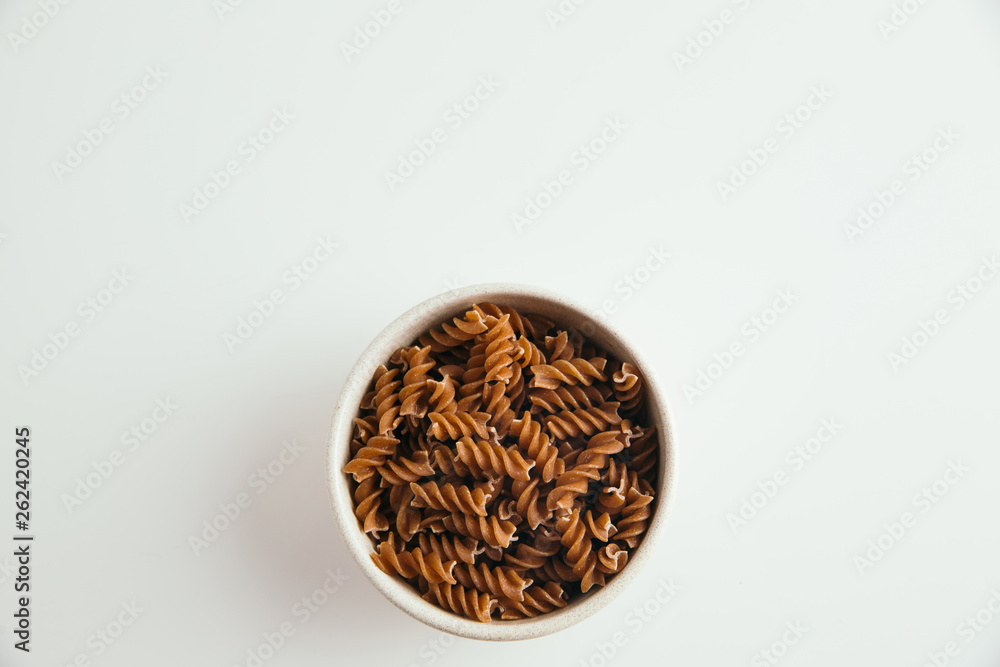 Whole grain fusilli pasta on white background, top view Whole grain fusilli pasta on white background, top view