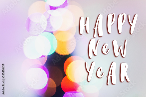 happy new year text sign on colorful christmas lights. bright bokeh. magical time. space for text. seasonal greetings concept. winter holidays greeting concept