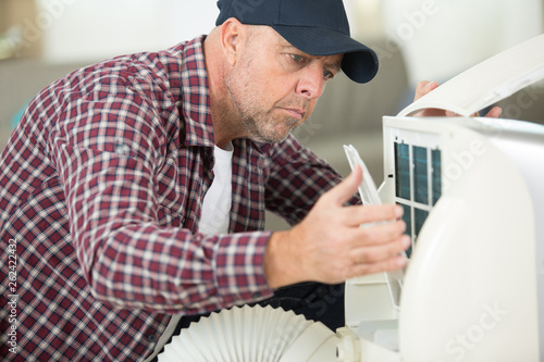 portrait of a man adjusting air conditioning system