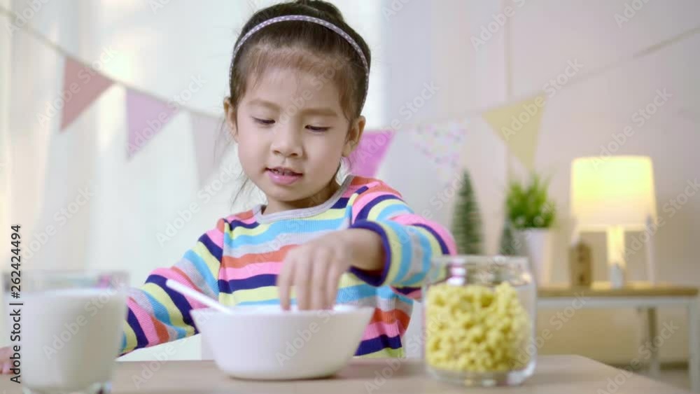Little asian child girl is eating cereal with milk on the morning, Healthy food habits concept Little asian child girl is eating cereal with milk on the morning, Healthy food habits concept