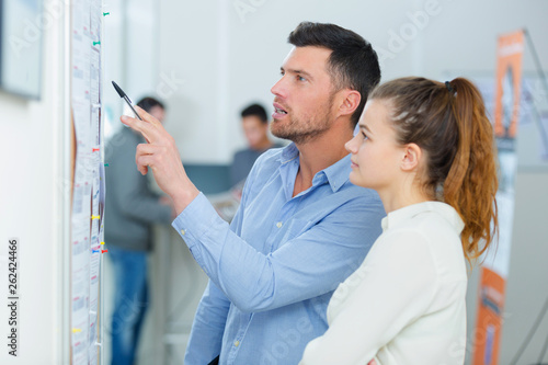man pointing at document stick on wall