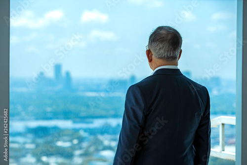 senior male businessman standing looking out the window  Background of tall buildings in the city's business district