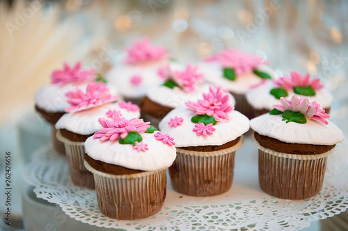 Cake for a buffet table. A group of small cupcakes decorated with pink cream flowers.
