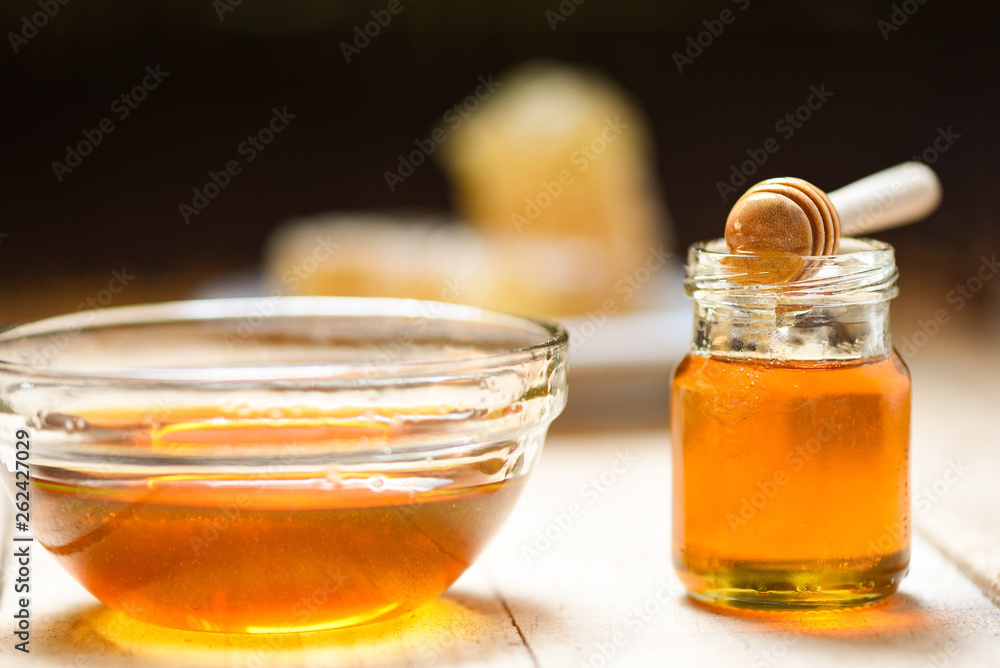 Fresh honey healthy food / Close up of yellow sweet honey in bowl and jar glass with wooden dipper Fresh honey healthy food / Close up of yellow sweet honey in bowl and jar glass with wooden dipper