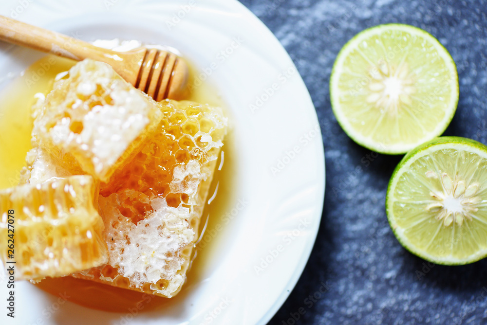 Fresh honey and lemon lime / Close up of yellow sweet honeycomb slice on white plate