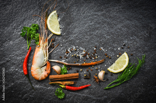 Shrimp prawn cooked shellfish seafood with lemon tomato herbs and spices on dark background