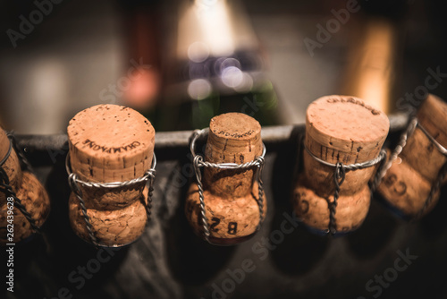 Unchained champagne corks in series with blurred wine bottles on the background photo