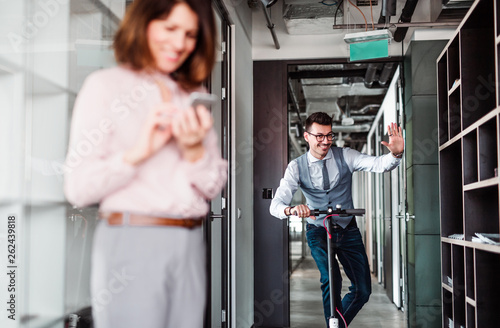 Young businessman with scooter in an office building, taking a break.