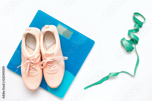 Athlete's set. Sports equipment - running shoes, scales, measuring tape on white background. Female fitness exercise concept.The combination of coral and turquoise. Flat lay, top view.