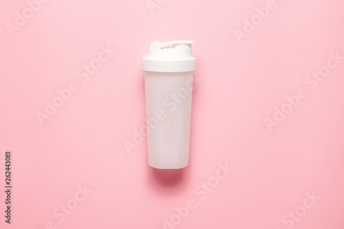 White plastic sports shaker on pastel pink  background.  Trendy athletics and sport minimal  concept. Female fitness.Flat lay, top view.  photo
