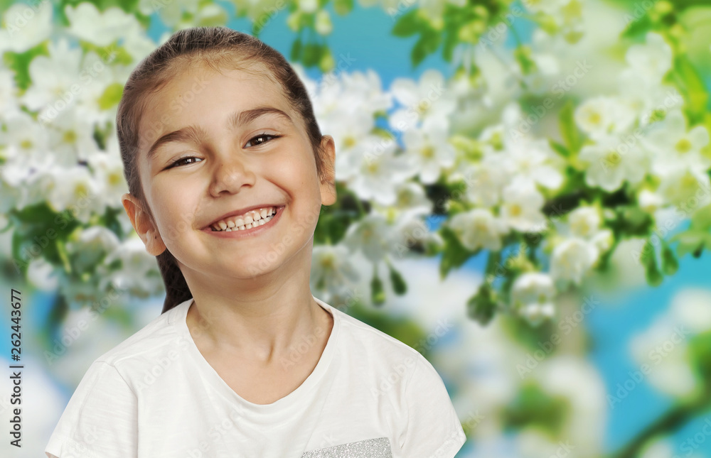 Happy healthy cute child girl on the blurry spring flowers background. Blooming garden. Spring time Happy healthy cute child girl on the blurry spring flowers background. Blooming garden. Spring time