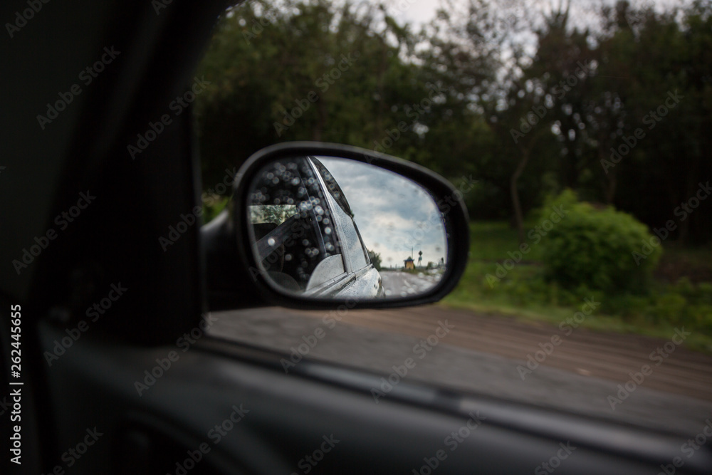 The reflection of road in the side view mirror. Travel concept. Bad weather and grey sky.