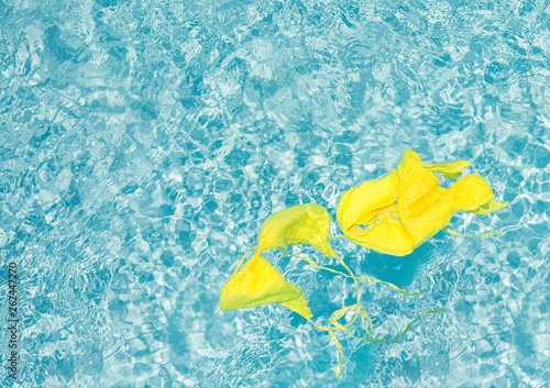 Yellow bikini in clean blue water of the pool. © flowertiare