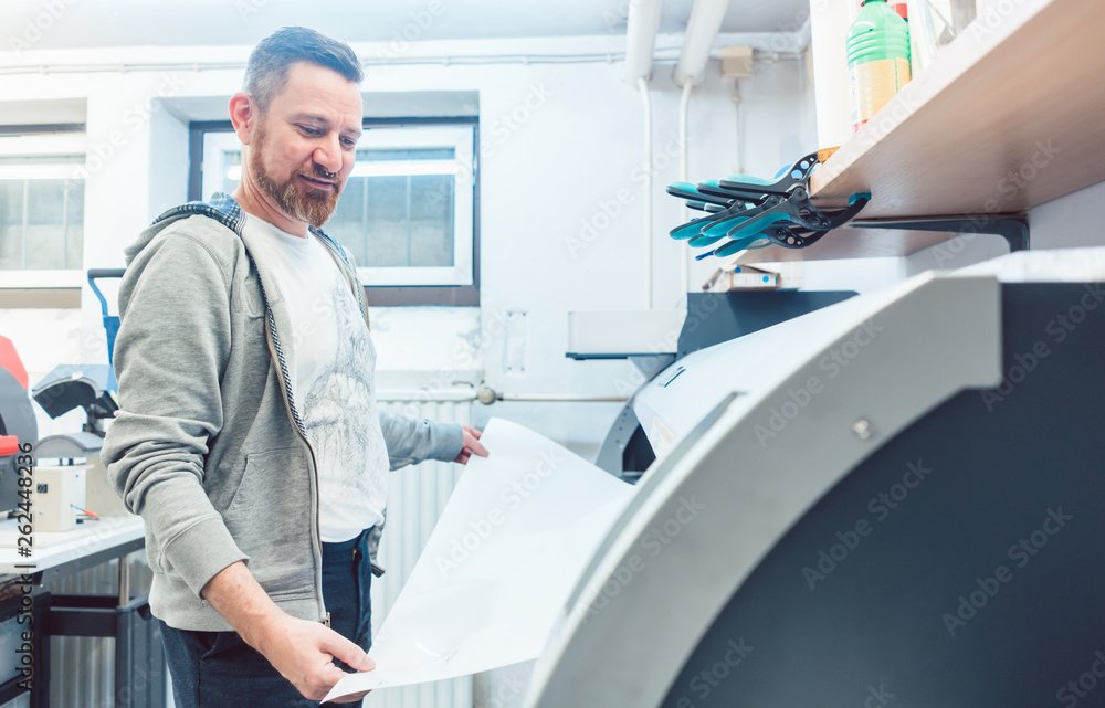 Man working on large format printer in advertising material agency Man working on large format printer in advertising material agency