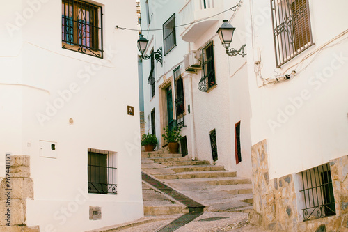 Beautiful narrow street in the old town with white houses and a cobblestone road. Altea, Spain