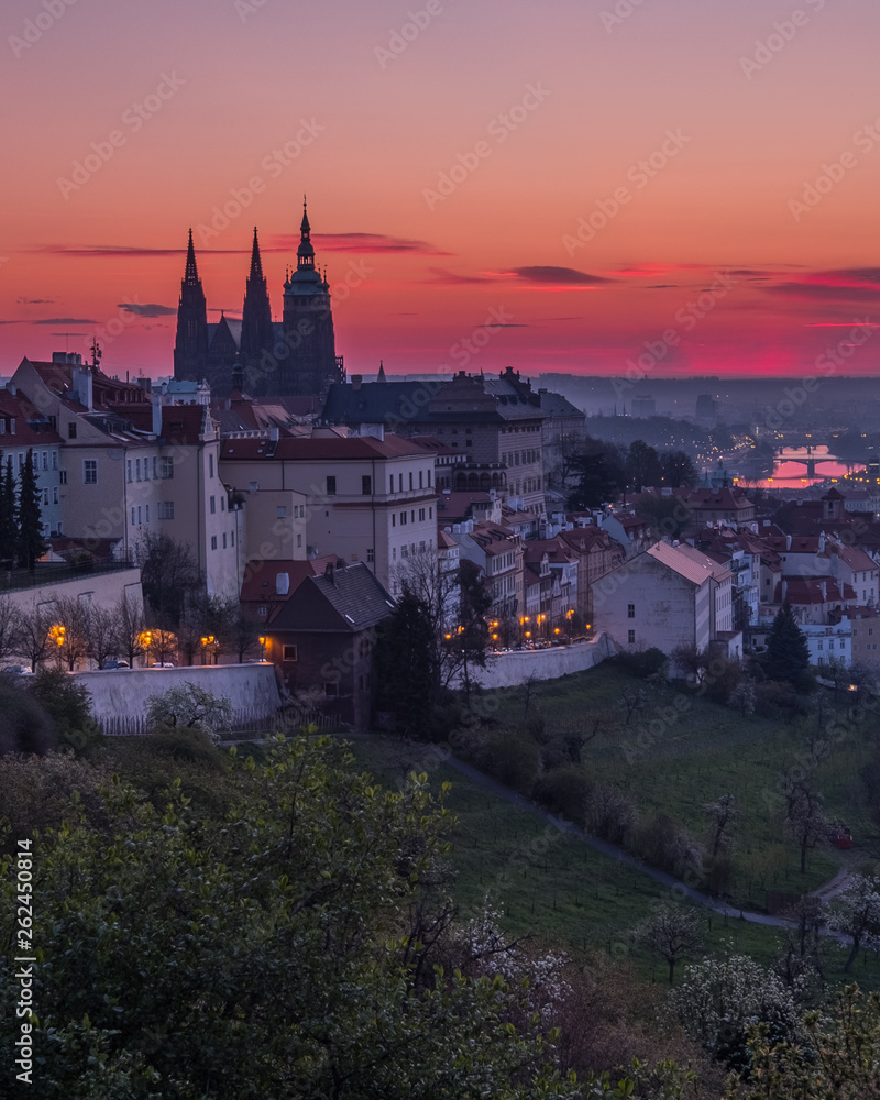 A beautiful spring view of Prague at sunrise from Petrin hill. Prague Castle and St. Vitus Cathedral on the left and a golden rising sun in the background