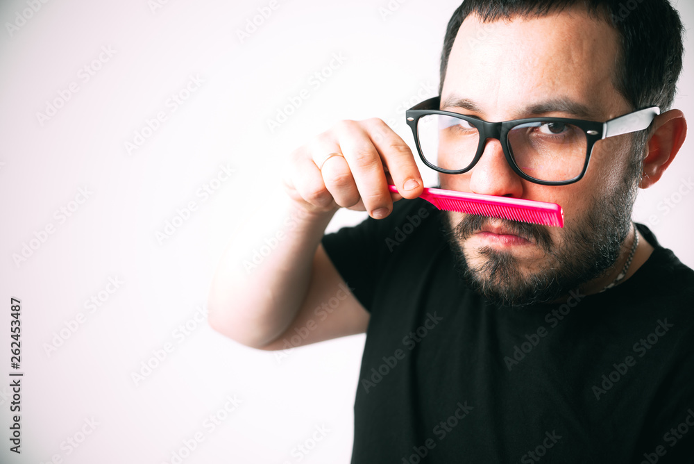 man with glasses combing his beard with a pink comb man with glasses combing his beard with a pink comb
