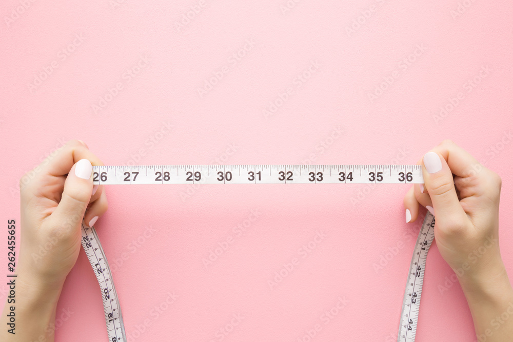 Unfolded white tape measure, White measuring tape isolated on pink  background. Close the tailor measuring tape on a pink background. The  concept of sports, diet, fitness, healthy eating. Copy space Stock Photo