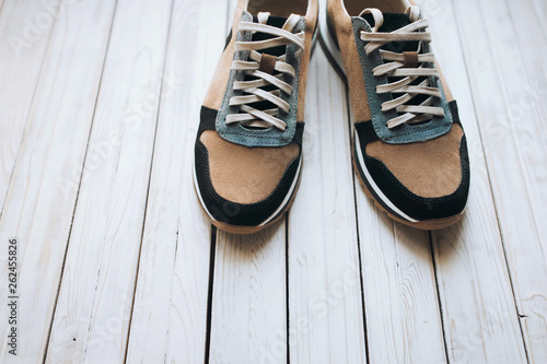 A new pair of suede sneakers on a white rustic wooden background. The concept of jog and sports shoes.