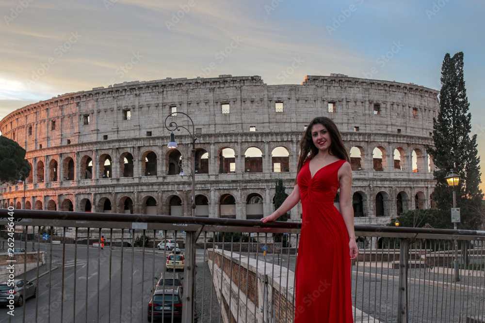 Pretty young girl in red dress in front of Colosseum, Rome, Italy. Rome symbol.