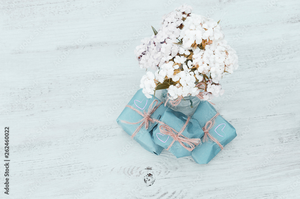 bouquet of flowers and gift boxes on a wooden background, delicate colors bouquet of flowers and gift boxes on a wooden background, delicate colors
