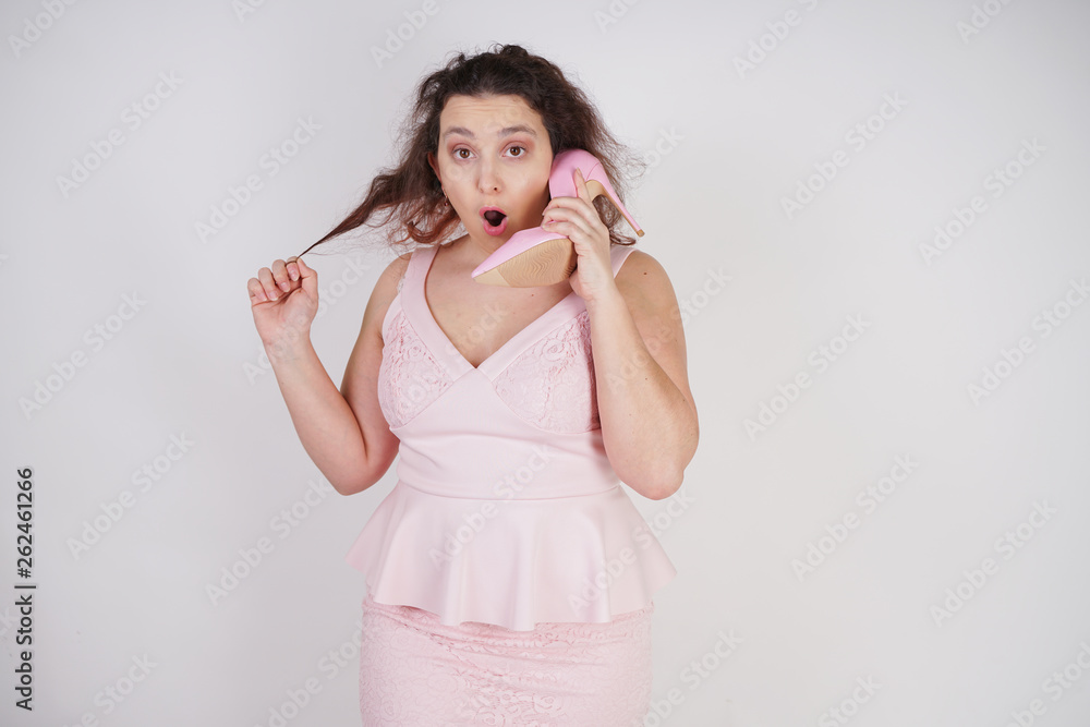 pretty plump woman in pink dress with patent leather stiletto heels on white background in Studio pretty plump woman in pink dress with patent leather stiletto heels on white background in Studio