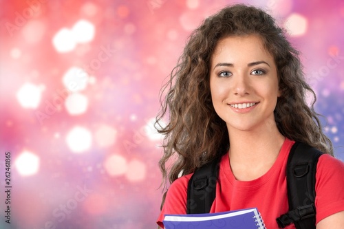 Portrait of a cute young student girl holding colorful notebook, isolated on background