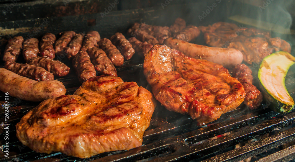 Juicy pork steaks, sausages and minced meat cevapcici on charcoal barbecue.