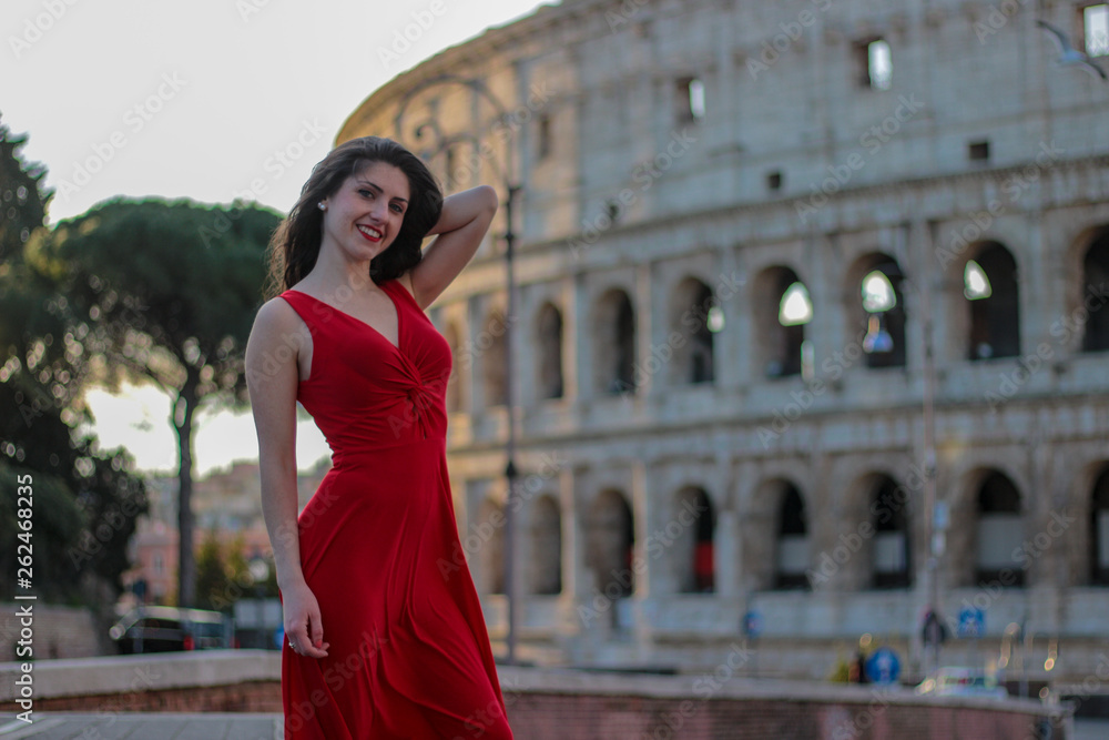 Pretty young girl in red dress in front of Colosseum, Rome, Italy. Rome symbol.