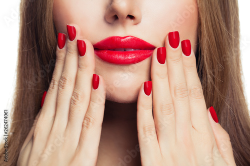 Red manicure nails and red female lips closeup