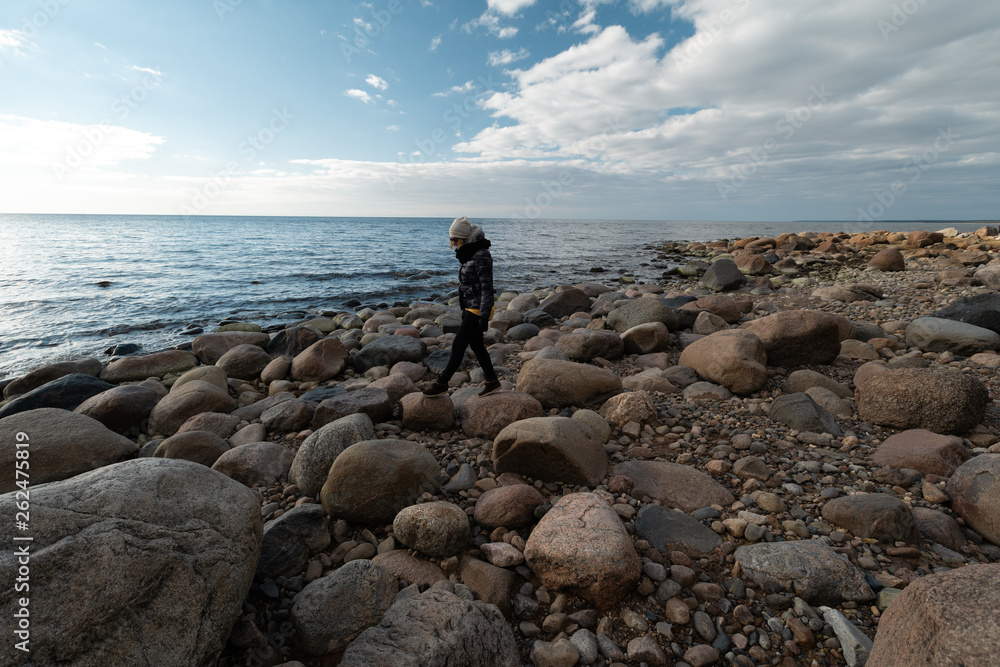 Young archaeologist on a boulder beach looking for exotic rocks on a coastline of a Baltic Sea