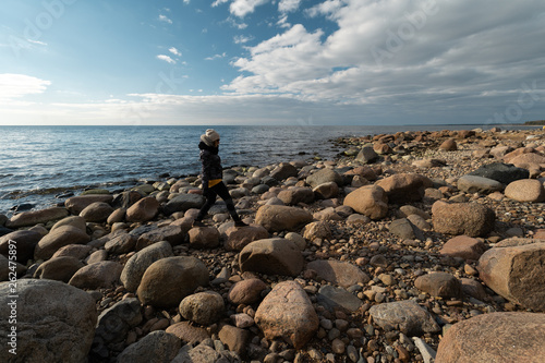 Young archaeologist on a boulder beach looking for exotic rocks on a coastline of a Baltic Sea