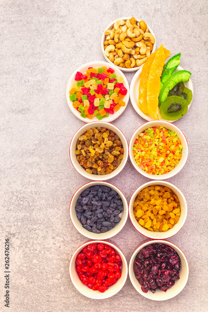 Dried and candied fruit and cashew nuts. Assorted in ceramic bowls on a stone background. Healthy vegetarian (vegan) food concept, top view, close up. Dried and candied fruit and cashew nuts. Assorted in ceramic bowls on a stone background. Healthy vegetarian (vegan) food concept, top view, close up.