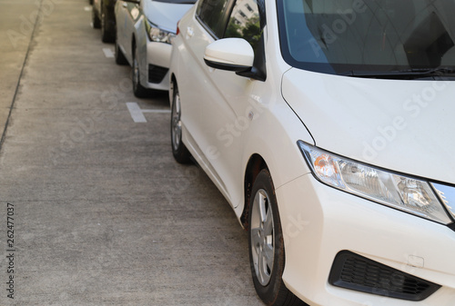 Closeup of front side of white car parking in parking area beside the street.