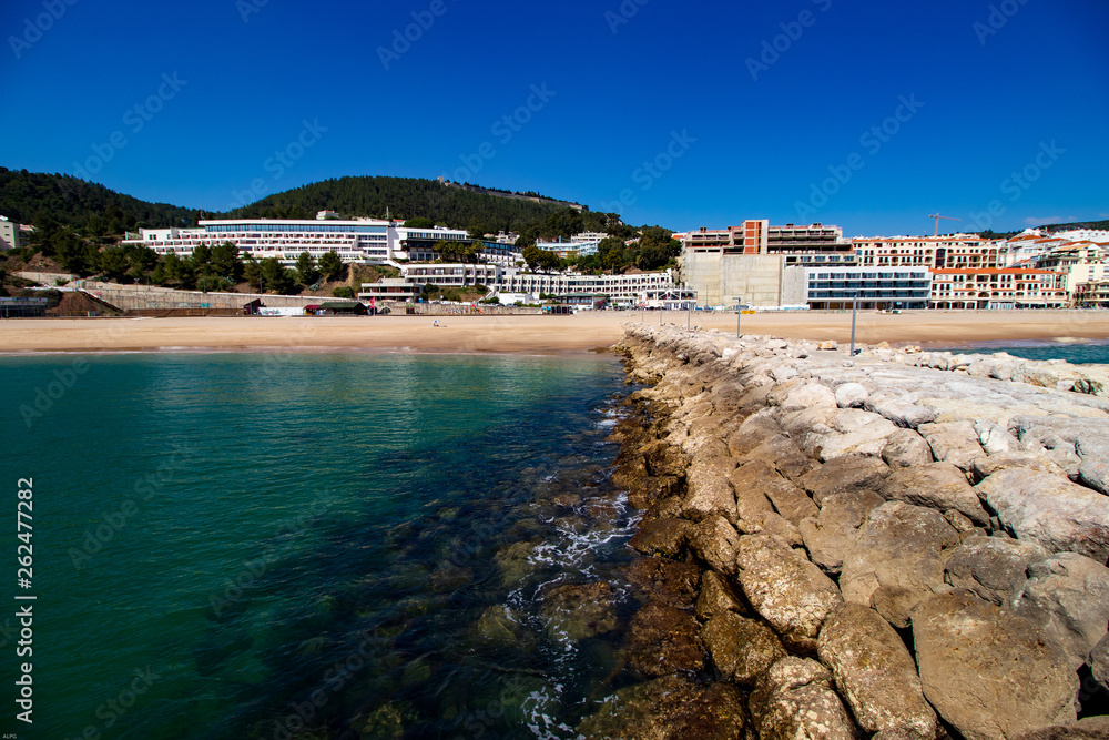 Rocks under transparent blue water with mountains in background, Ssesimbra