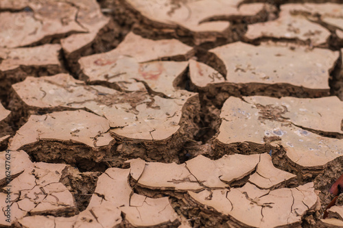 Deep cracks earth in the red land as a symbol of hot climate and drought.