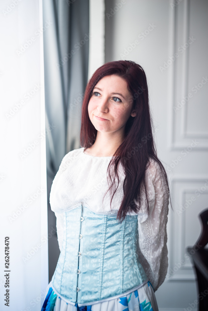 young caucasian funny woman in a sky blue corset and white shirt ready for historical ball dance