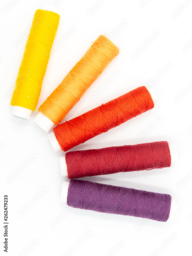 sewing threads in yellow, orange, red and purple isolated on white background, arranged in a semicircle
