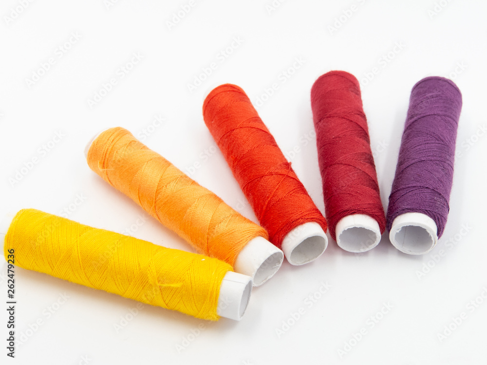 sewing threads in yellow, orange, red and purple isolated on white background, arranged in a semicircle sewing threads in yellow, orange, red and purple isolated on white background, arranged in a semicircle