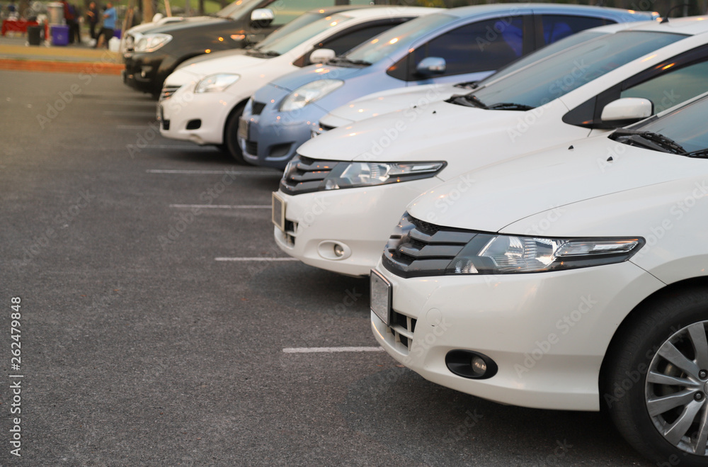 Closeup of front side of white car and other cars parking in outdoor parking area in twilight evening. Closeup of front side of white car and other cars parking in outdoor parking area in twilight evening.