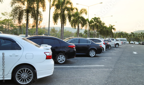 Closeup of rear, back side of white car and  other cars parking in outdoor parking lot with natural background in twilight evening.  © Amphon