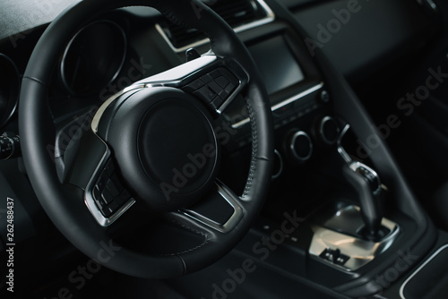 selective focus of steering wheel near gear shift handle in luxury car