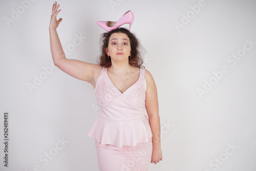 pretty plump woman in pink dress with patent leather stiletto heels on white background in Studio