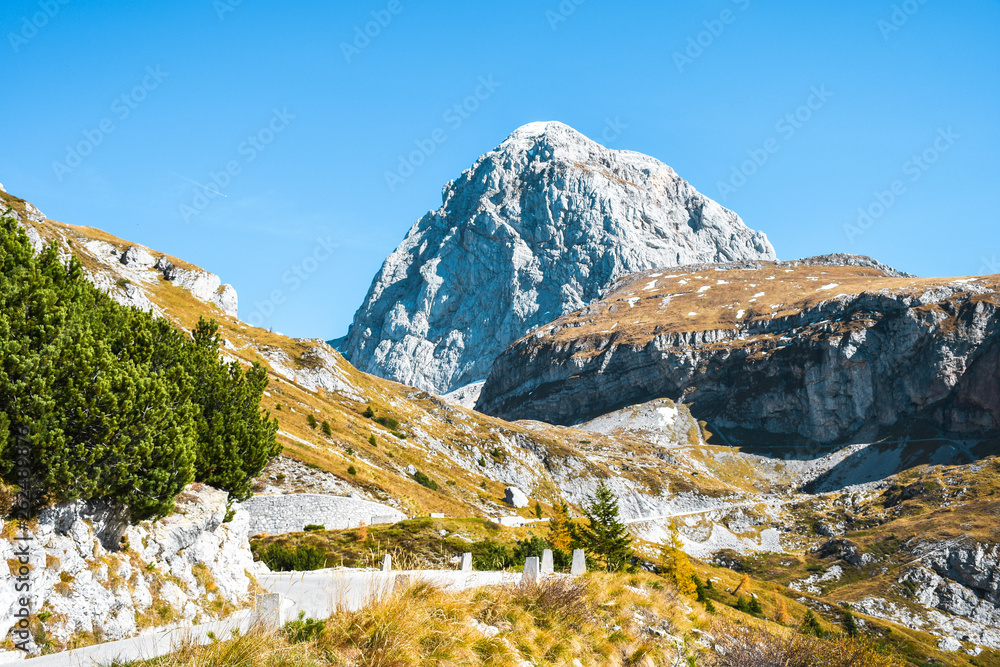 View of a beautiful Mangart mountain peak and old military road on a sunny autumn colors day, Slovenia