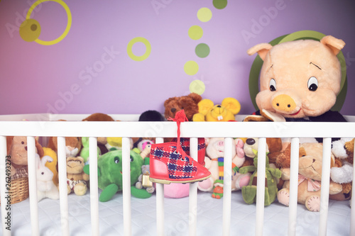 Group of colorful fluffy stuffed animal toys closeup with hanging red small baby shoe on a white crib fence  © Tadej